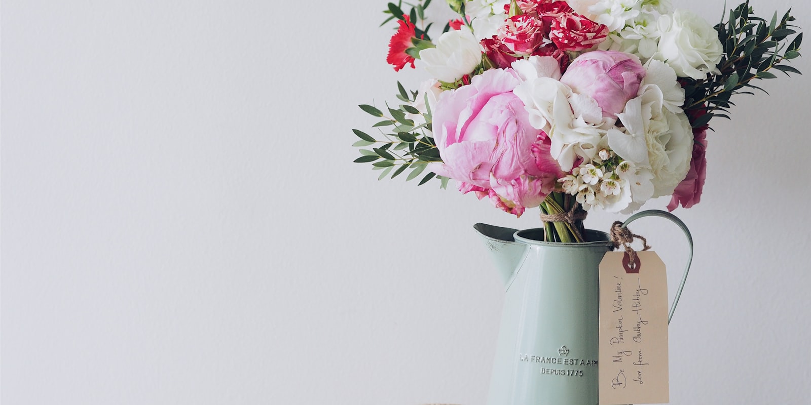 Peonies and carnations arranged in a vintage pitcher