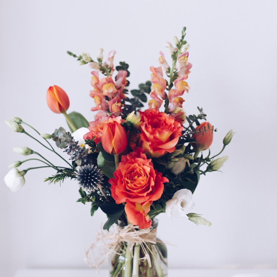 Orange roses and tulips arranged in a vase with wild greenery